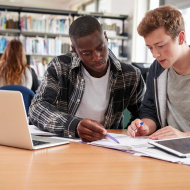 Teenagers looking at paperwork in libary