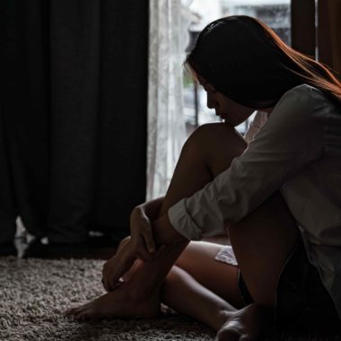 girl sat curled up in the dark