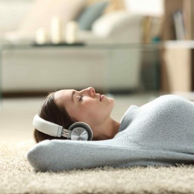 girl lying on living room floor with headphones on