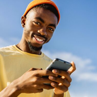 Teen holding mobile smiling into camera