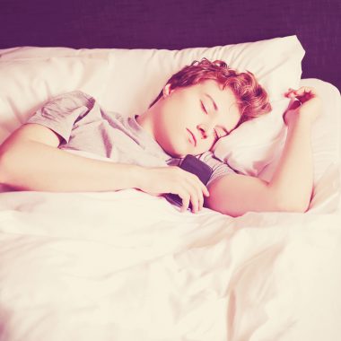 Teen asleep on bed with phone