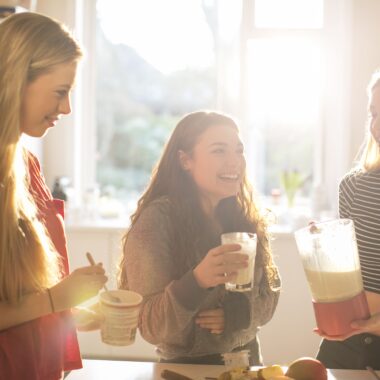 Group of 3 friends smiling whilst making a smoothie