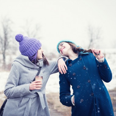 Girls standing in snow holding coffee