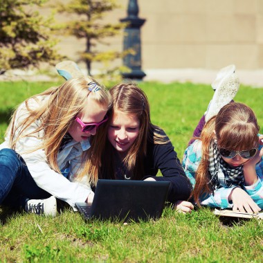 Girls on grass looking at laptop