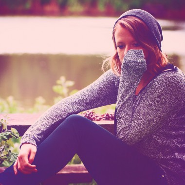 Girl sat by lake looking thoughtful