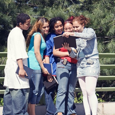 Group of teens looking at books outside