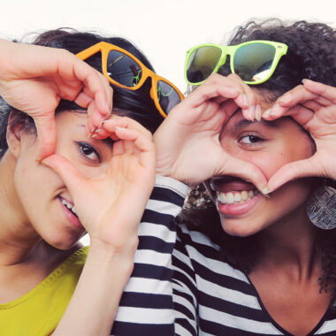 Two young girls making hearts with their hands