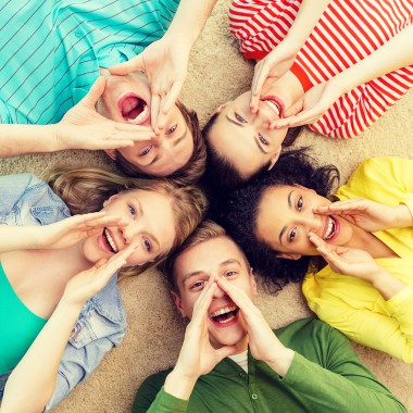 Five teenagers lying in the sand shouting up