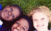 Three girls lying on the grass smiling at the camera