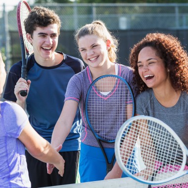 Teens laughing playing tennis