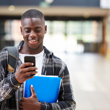 Male-College-Student-Reading-Text-Message-On-Mobile-Phone